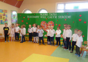 Dzieci ustawione w półkolu śpiewają piosenkę.
